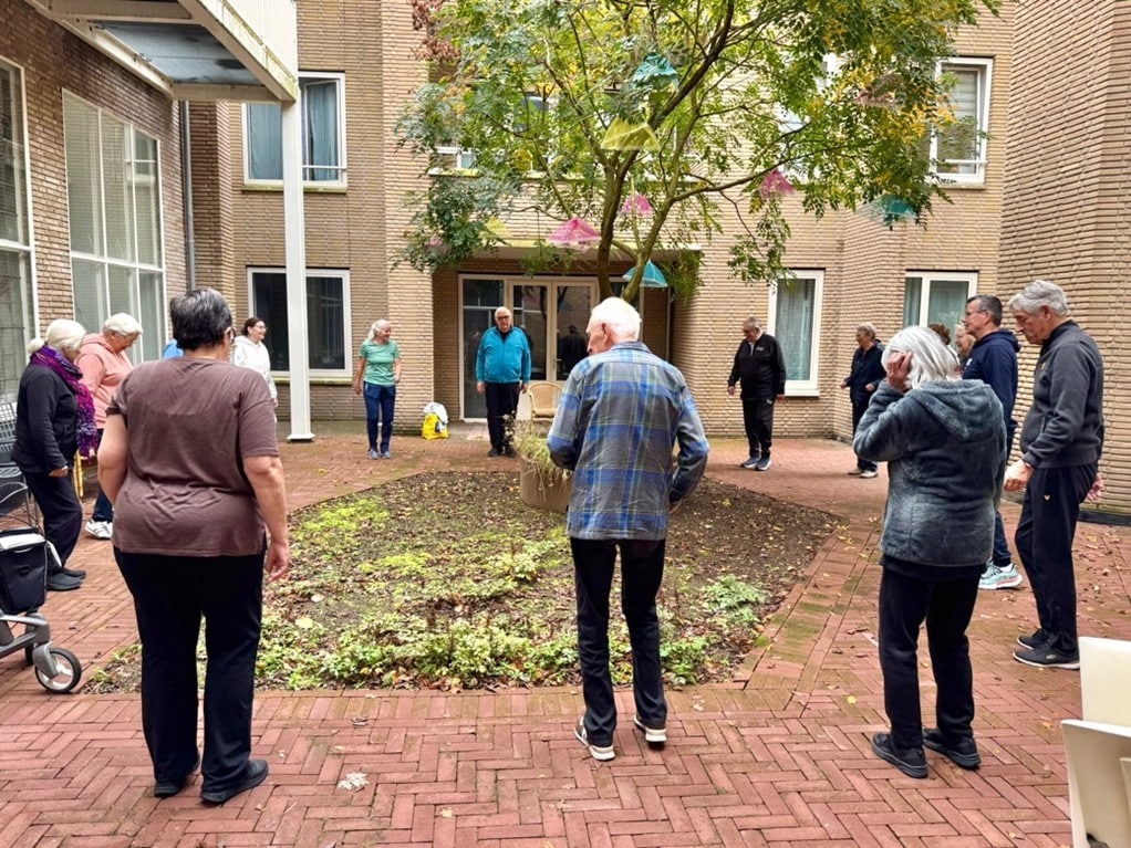 Senioren bewegen buiten op de binnenplaats van De Kroon.