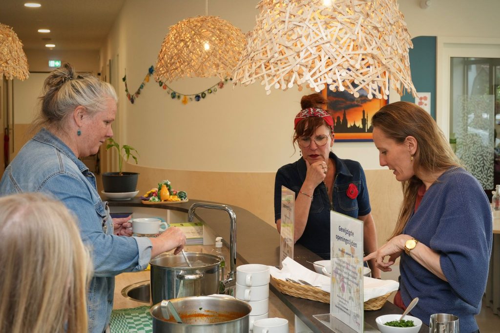 Beheerder van het buurthuis Mariëlle schenkt een kopje soep in achter de bar in het buurthuis,