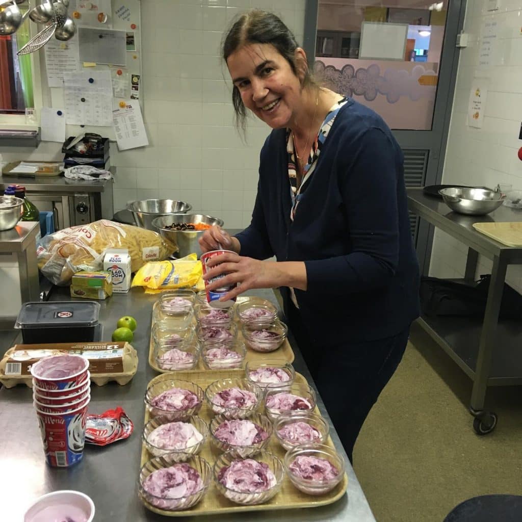 Een dame schept toetjes in een bakje.